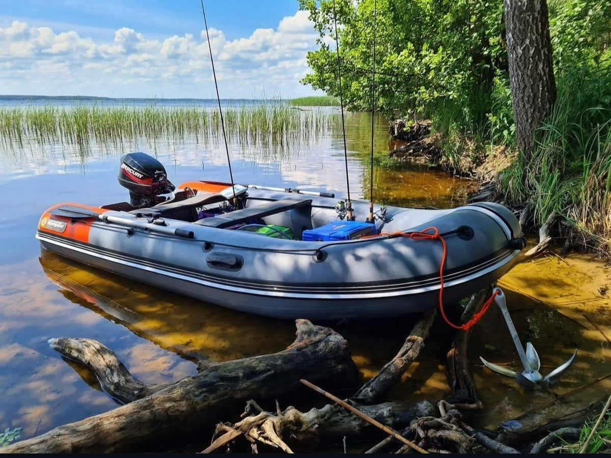 Grey Navigator inflatable boat on a lake shore with outboard motor, oars, fishing rods and anchor
