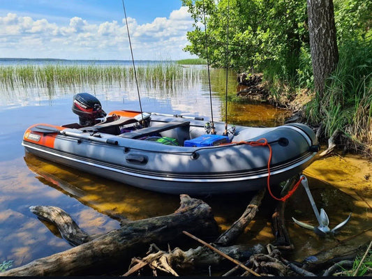 Grey Navigator inflatable boat on a lake shore with outboard motor, oars, fishing rods and anchor