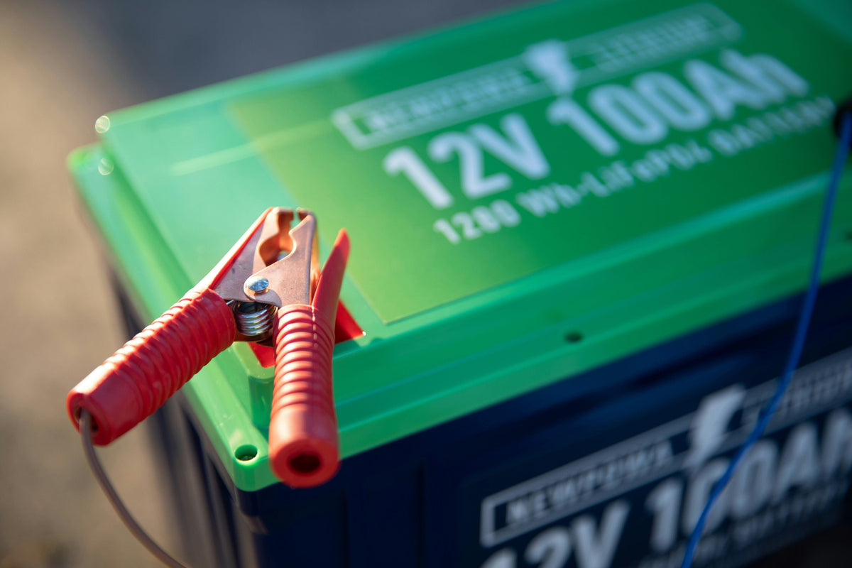 12V 100Ah LiFePO4 marine battery with a red charging clamp attached to the terminal