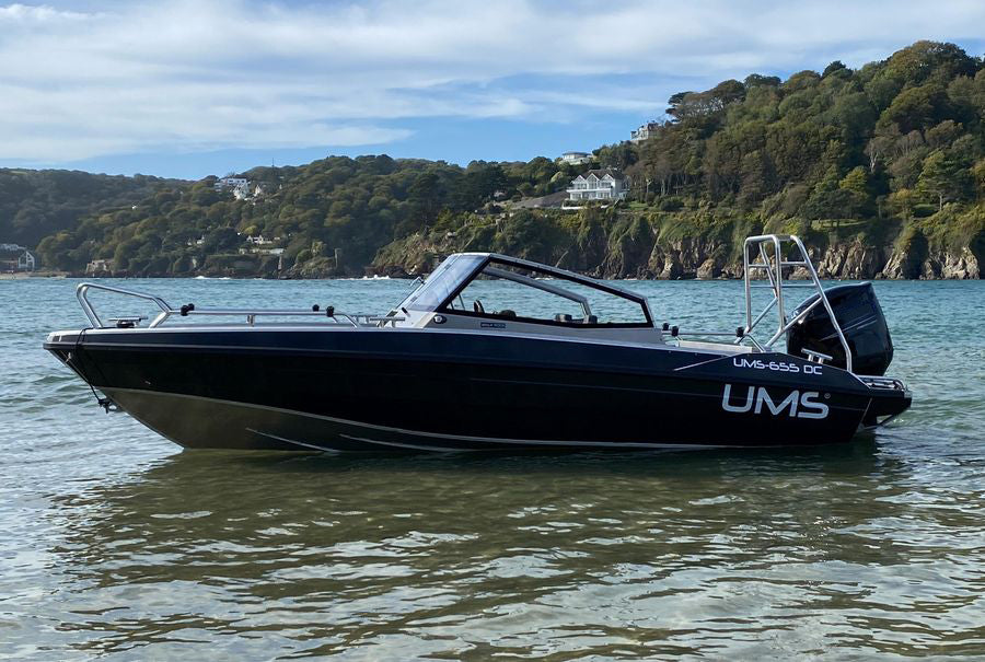 A side view of the UMS 655 DC aluminum boat anchored in shallow water.
