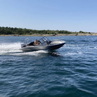 An aluminum UMS 545 DC 18ft boat speeding across open water, leaving a trail of wake behind.