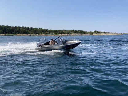 An aluminum UMS 545 DC 18ft boat speeding across open water, leaving a trail of wake behind.