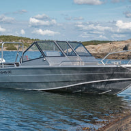 An aluminum UMS 545 DC boat anchored near a rocky shore.
