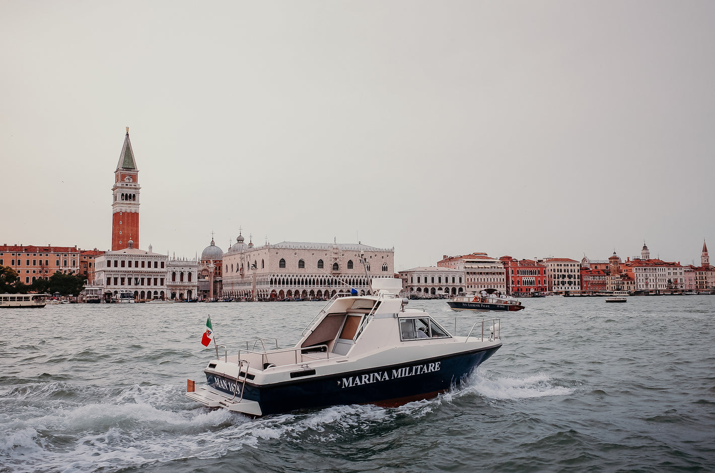 Motor boat cruising through a harbour with historic waterfront buildings in the background