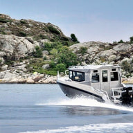 The UMS 865CAB aluminum boat cruising along a rocky shoreline.