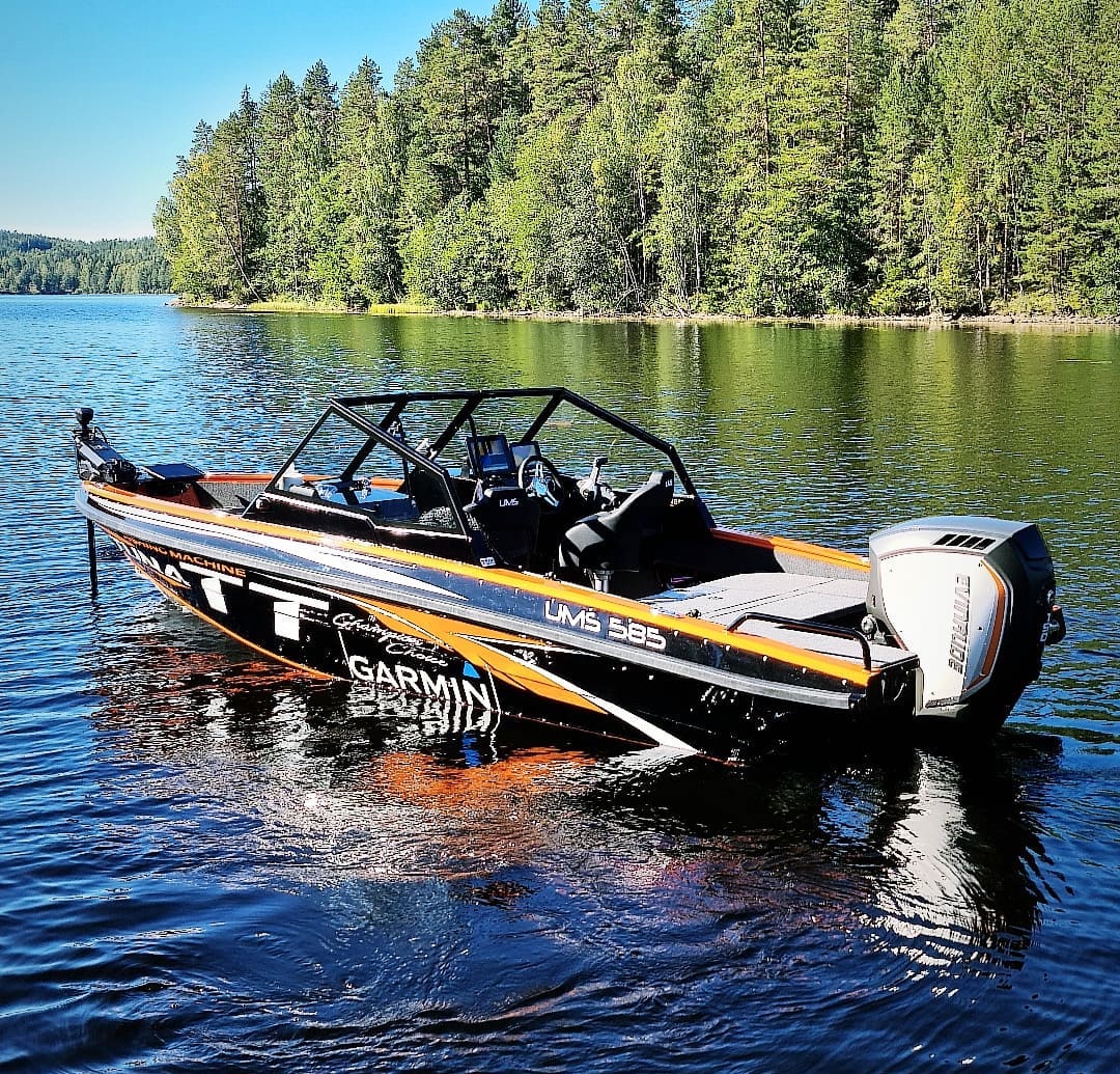 An aluminum UMS 585DC fishing boat with a sleek design floats on a calm lake.