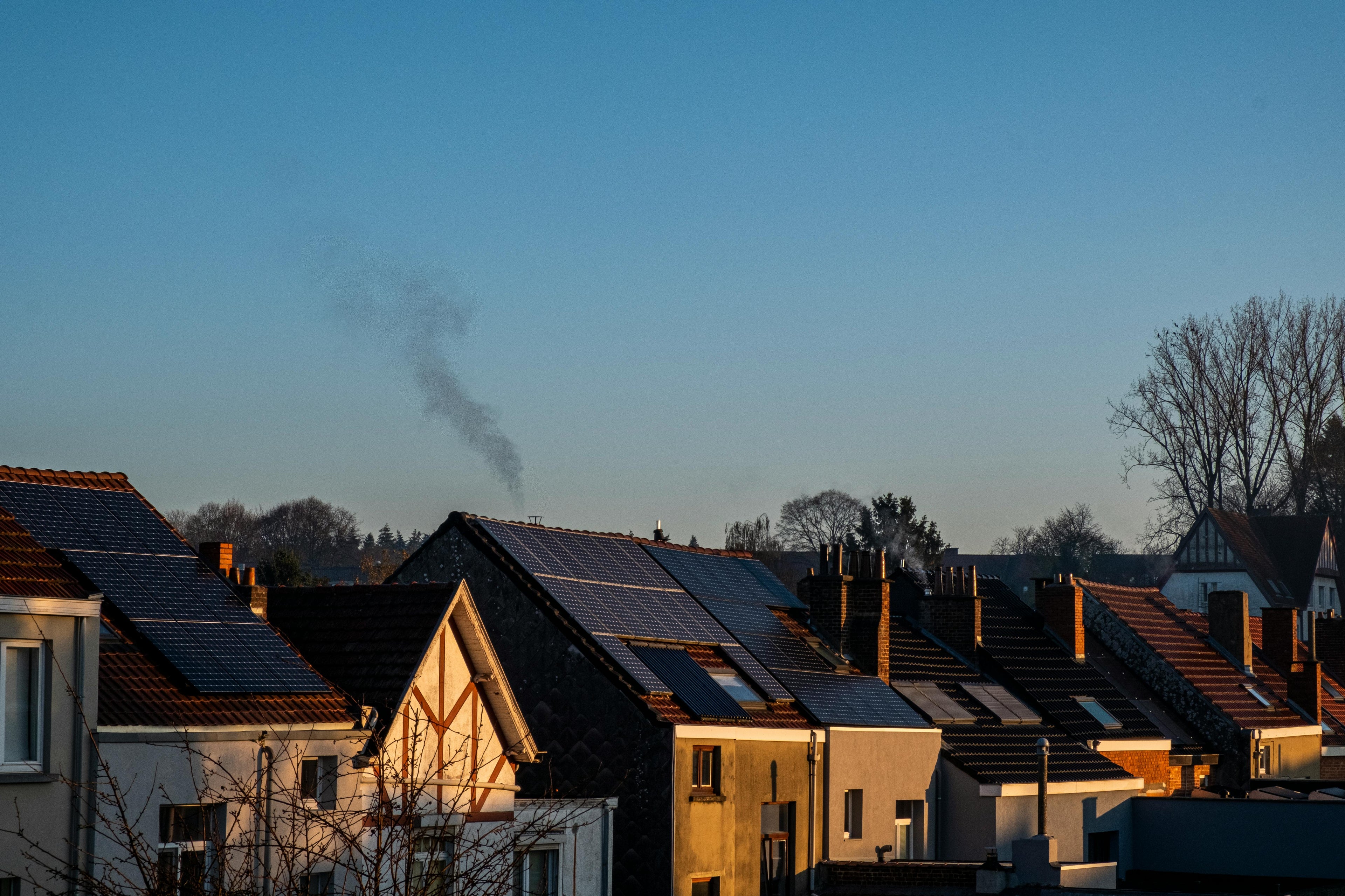 Row of houses with solar panels on rooftops against a clear blue sky.