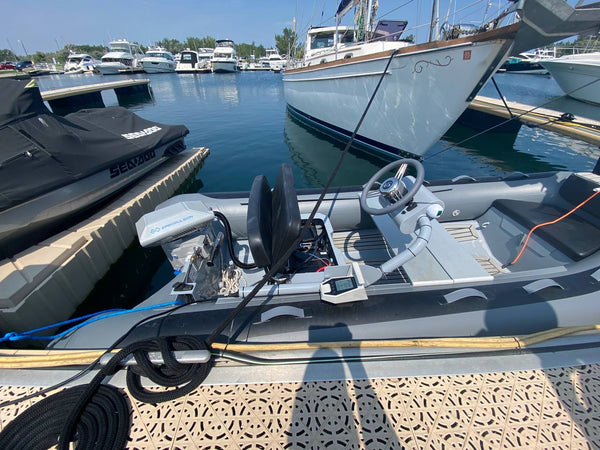 Side console of the RIB with steering wheel, ePropulsion remote throttle and display, and the Navy 6.0 Evo outboard behind the helm seat