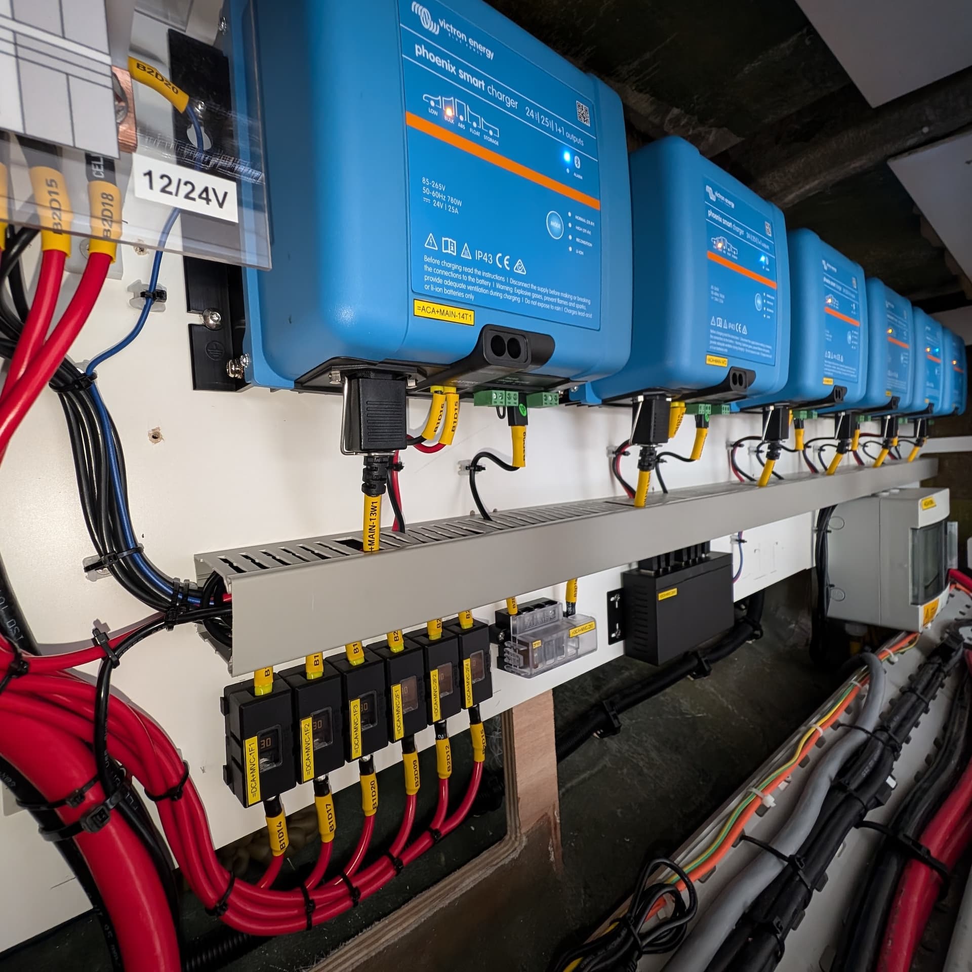 Row of blue power inverters with wiring and connectors on a panel.