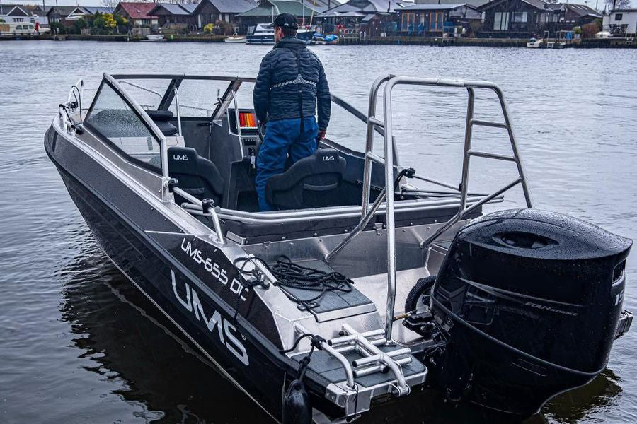 A man standing on the deck of the UMS 655 DC aluminum boat.